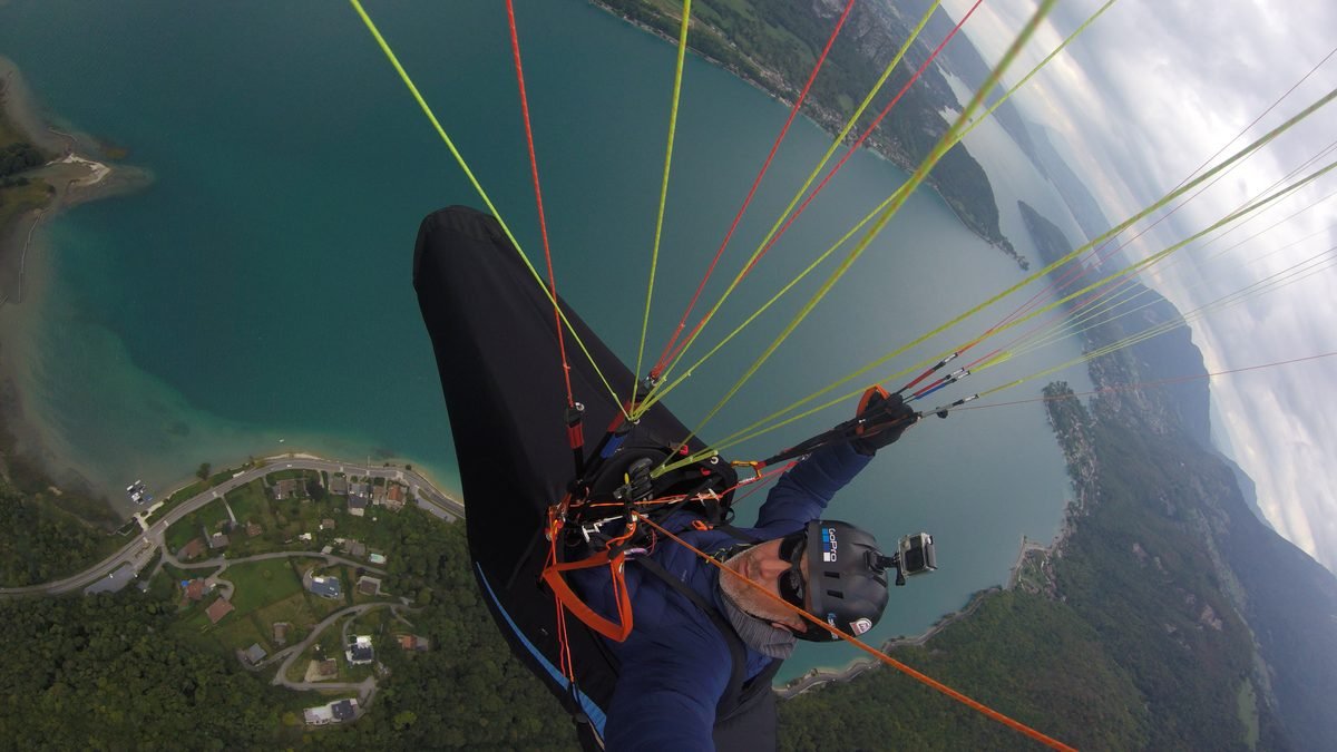 Piloto de parapente volando sobre lago en Argentina - Vuela Vuela Libre